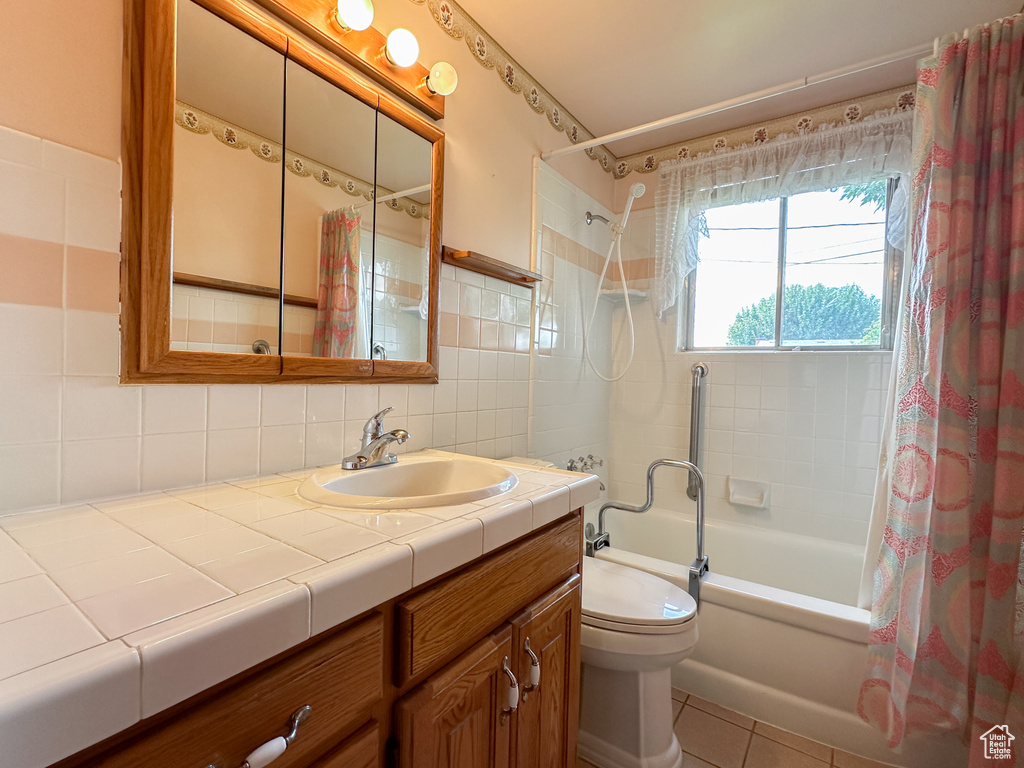 Full bathroom featuring vanity, tile patterned flooring, tile walls, toilet, and shower / bathtub combination with curtain