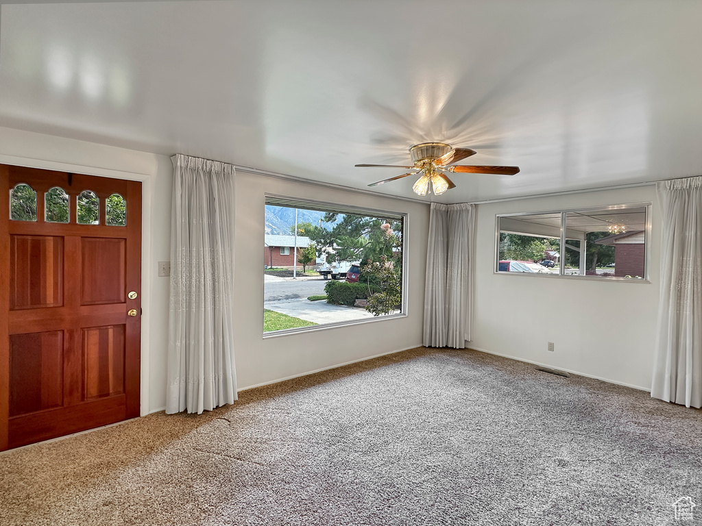 Carpeted foyer entrance featuring ceiling fan