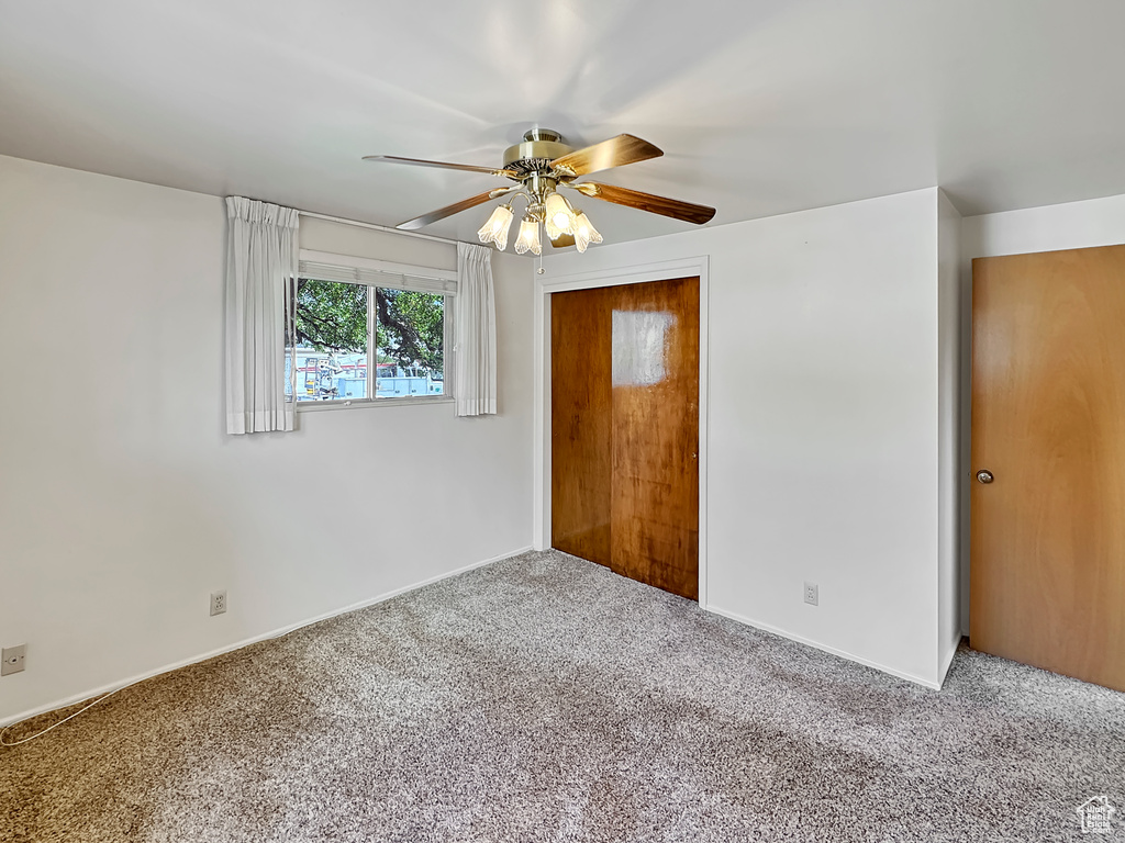 Carpeted empty room featuring ceiling fan