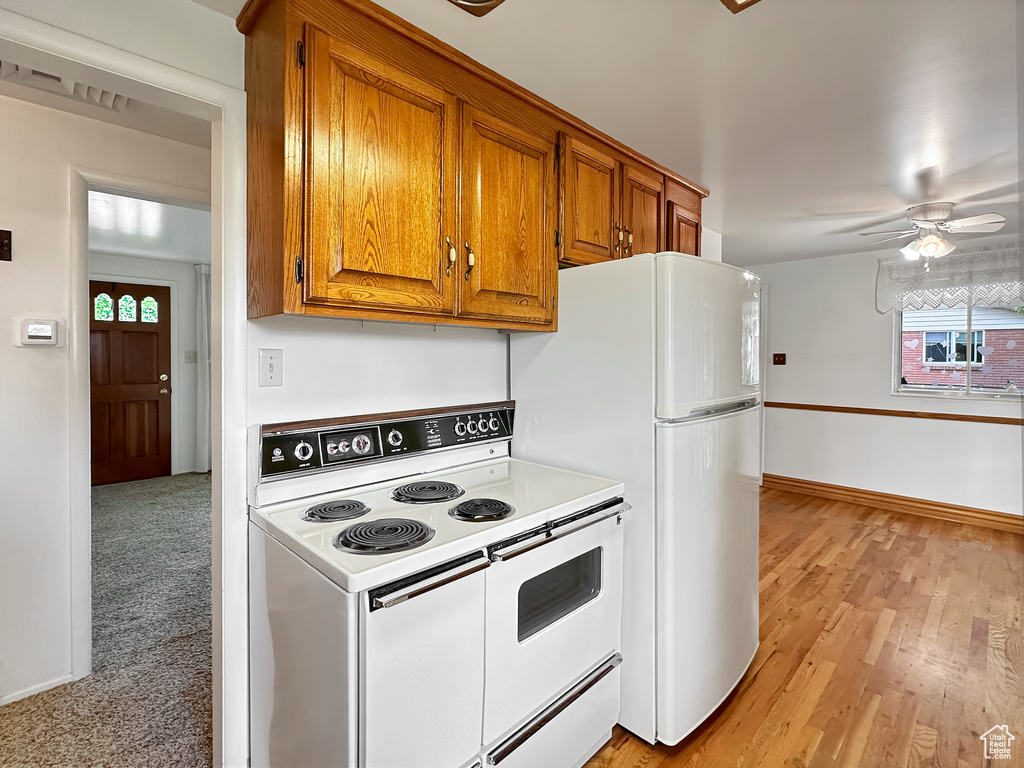 Kitchen featuring light wood-type flooring, white appliances, a healthy amount of sunlight, and ceiling fan