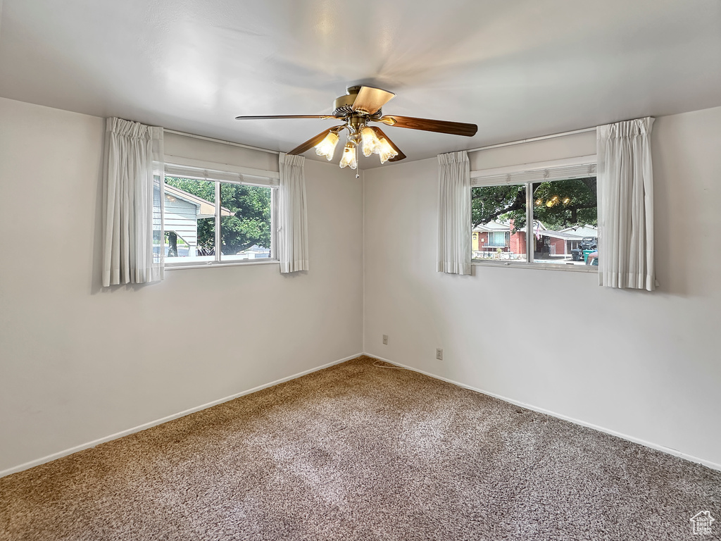 Carpeted empty room featuring ceiling fan