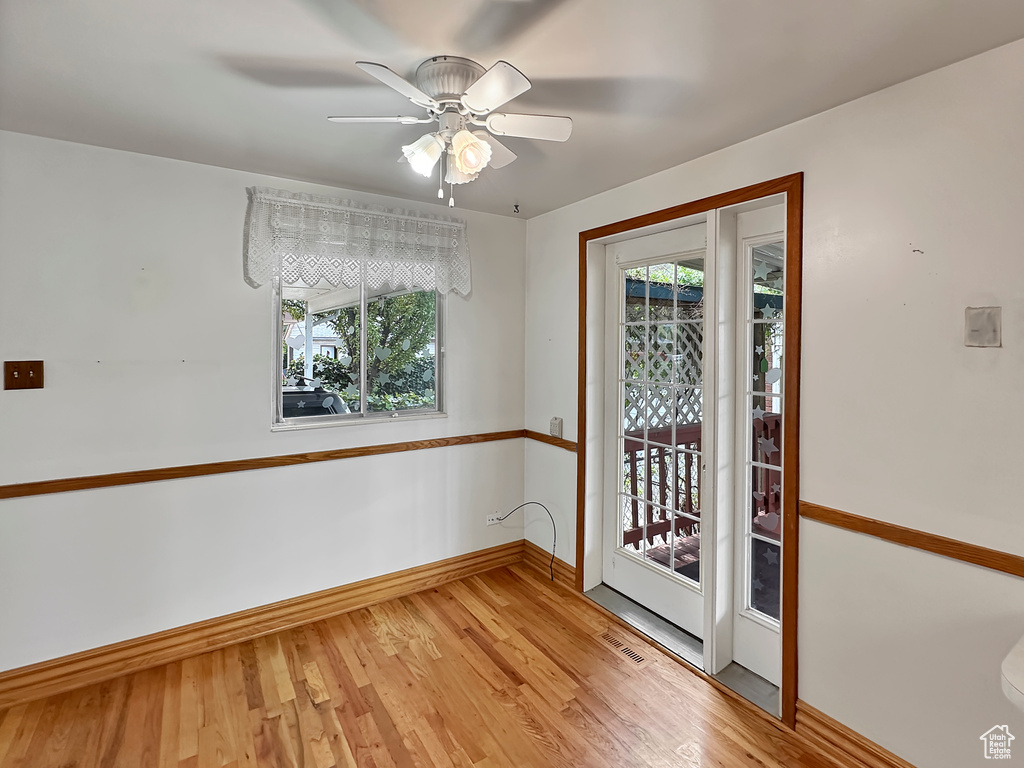 Empty room featuring ceiling fan, plenty of natural light, and light hardwood / wood-style flooring