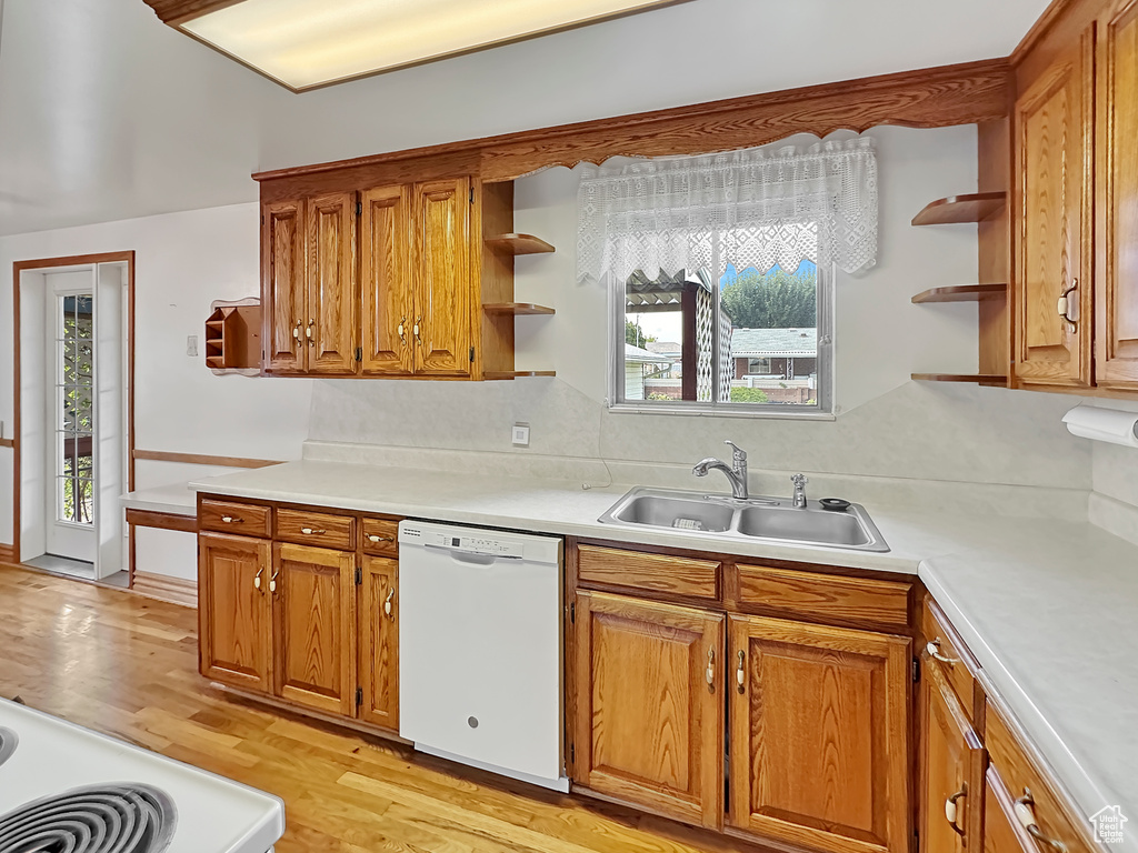 Kitchen with white dishwasher, sink, light wood-type flooring, and decorative backsplash