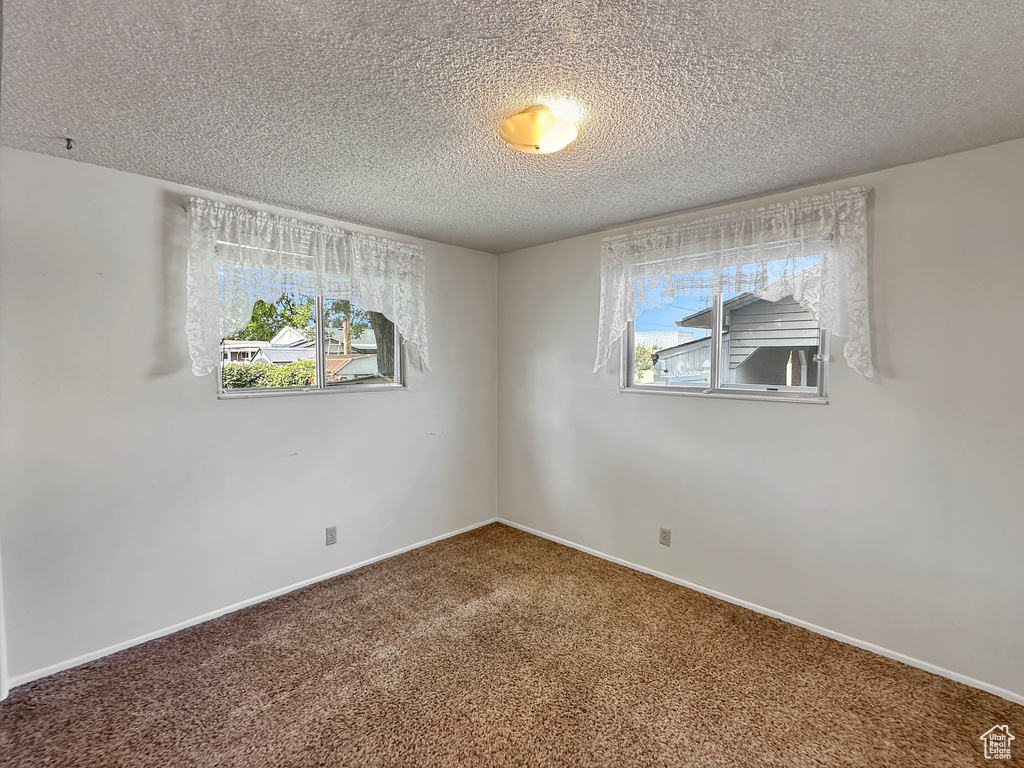 Carpeted spare room with a textured ceiling