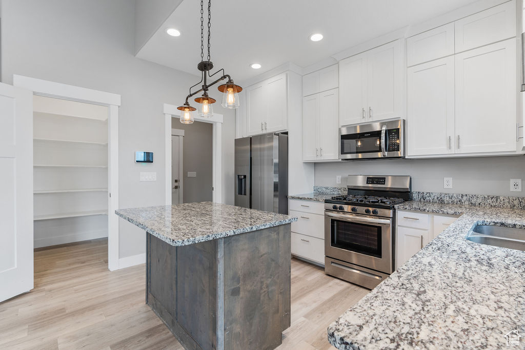 Kitchen featuring a center island, stainless steel appliances, white cabinetry, and light hardwood / wood-style floors