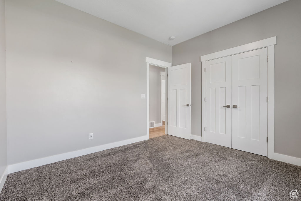 Unfurnished bedroom featuring carpet flooring and a closet