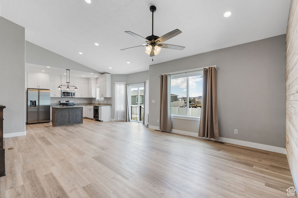 Unfurnished living room featuring vaulted ceiling, light hardwood / wood-style flooring, sink, and ceiling fan