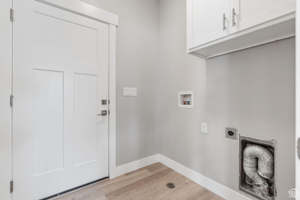 Laundry area with cabinets, light wood-type flooring, washer hookup, and hookup for an electric dryer