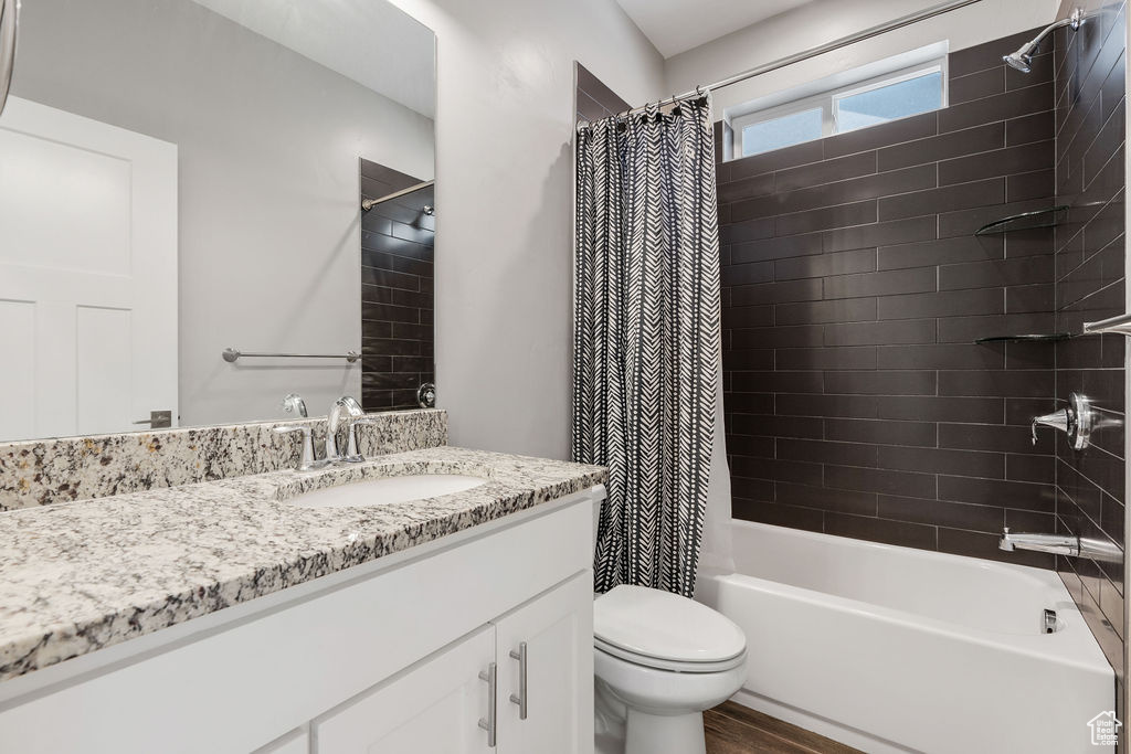 Full bathroom featuring vanity, toilet, hardwood / wood-style floors, and shower / bath combo with shower curtain