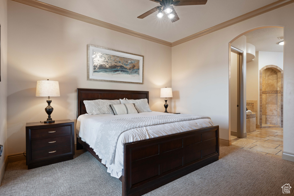 Carpeted bedroom with ceiling fan, crown molding, and ensuite bath