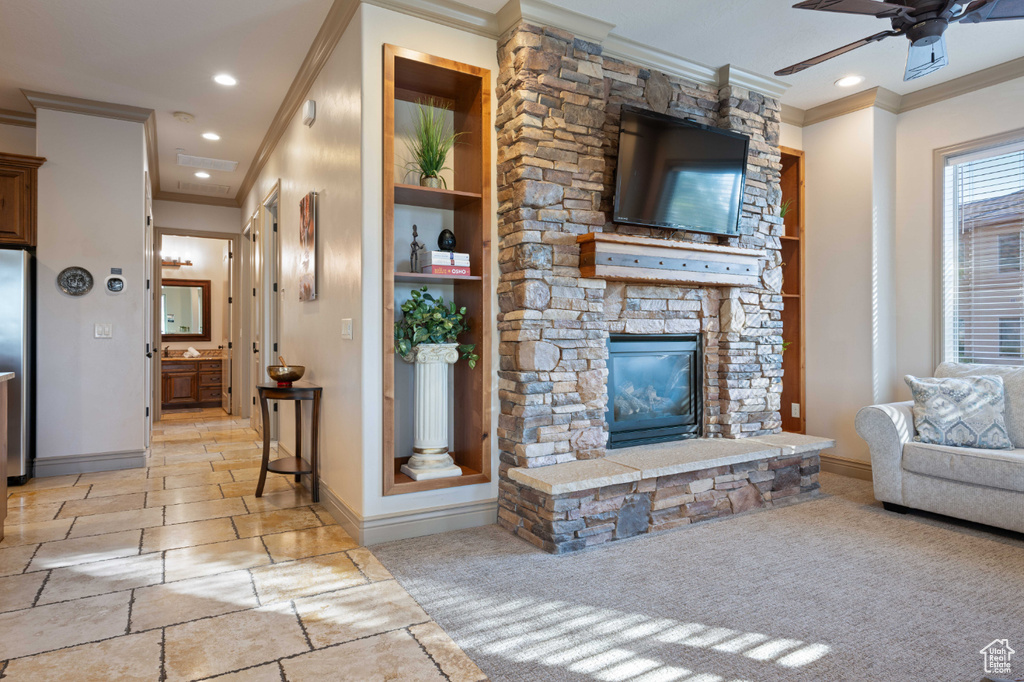 Carpeted living room with ceiling fan, a fireplace, and crown molding