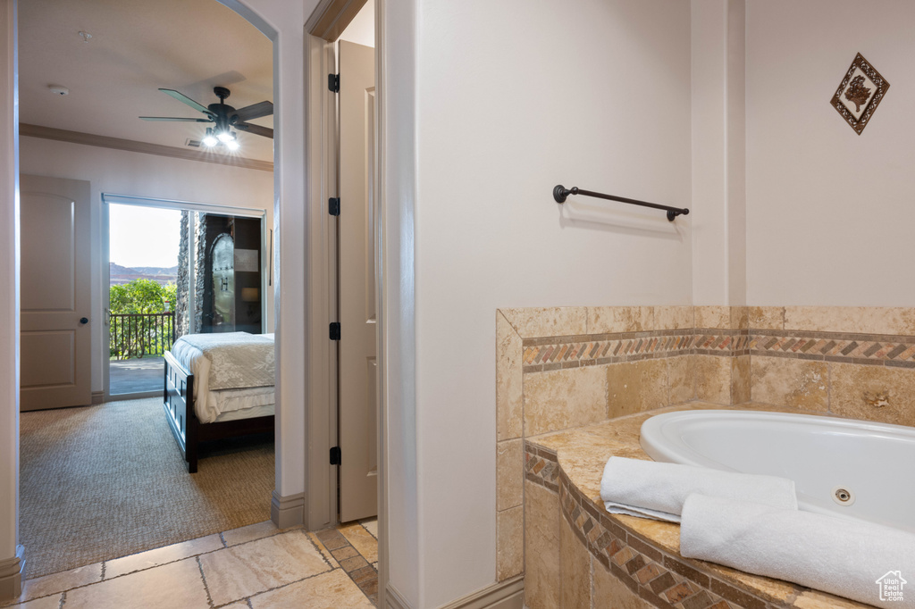 Bathroom with crown molding, a relaxing tiled tub, and ceiling fan