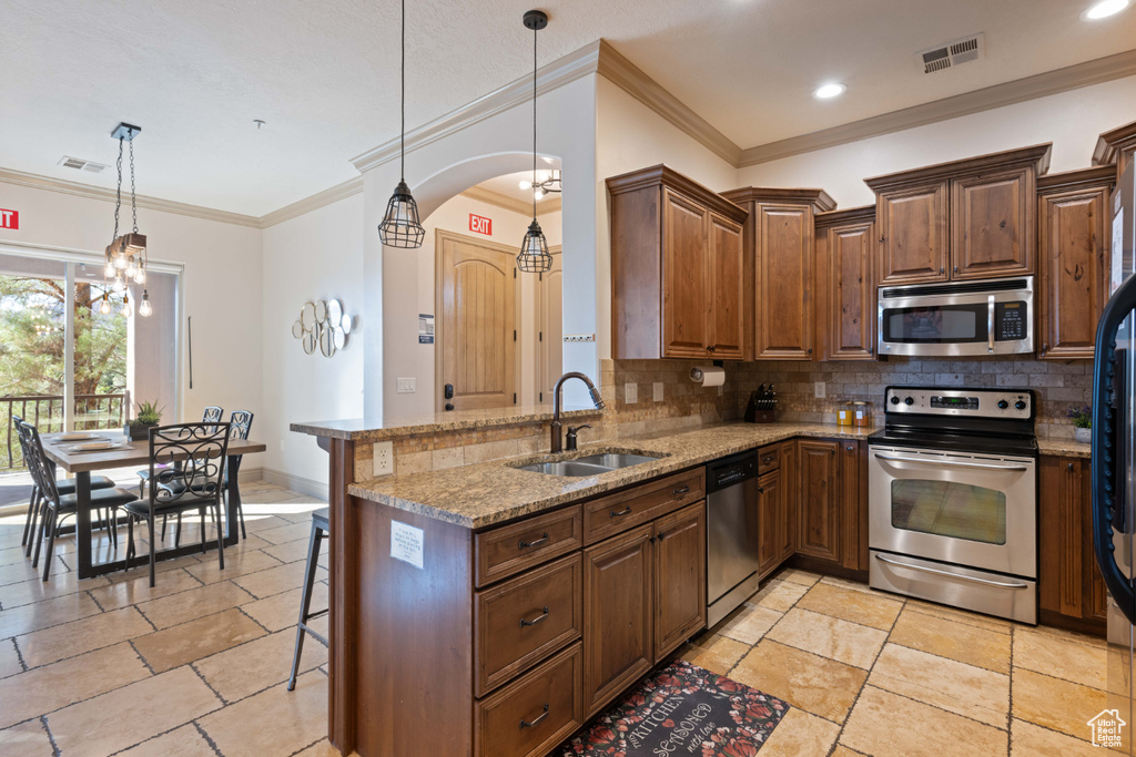 Kitchen featuring appliances with stainless steel finishes, a notable chandelier, sink, kitchen peninsula, and a kitchen bar