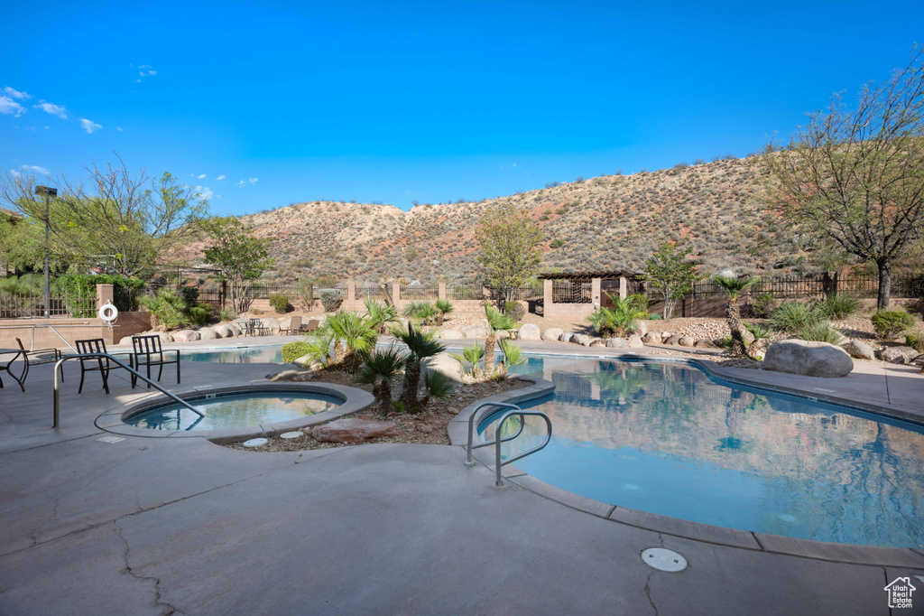 View of swimming pool with a community hot tub, a patio area, and a mountain view