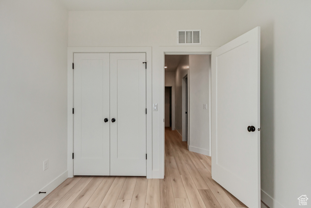 Unfurnished bedroom featuring light wood-type flooring and a closet