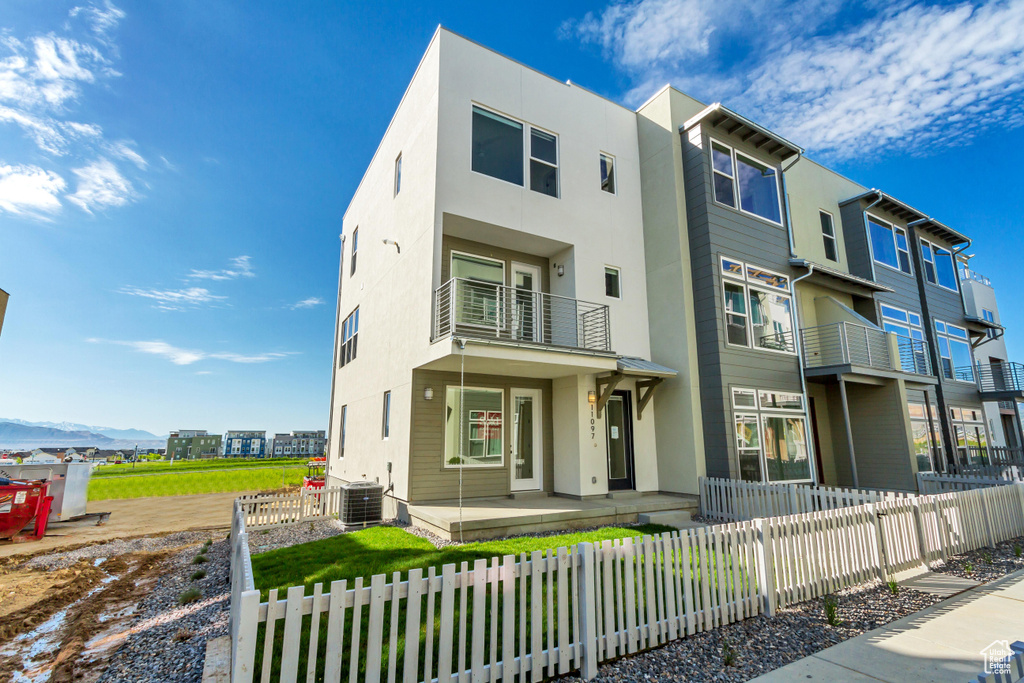 View of front of home featuring a balcony, a mountain view, and central AC unit