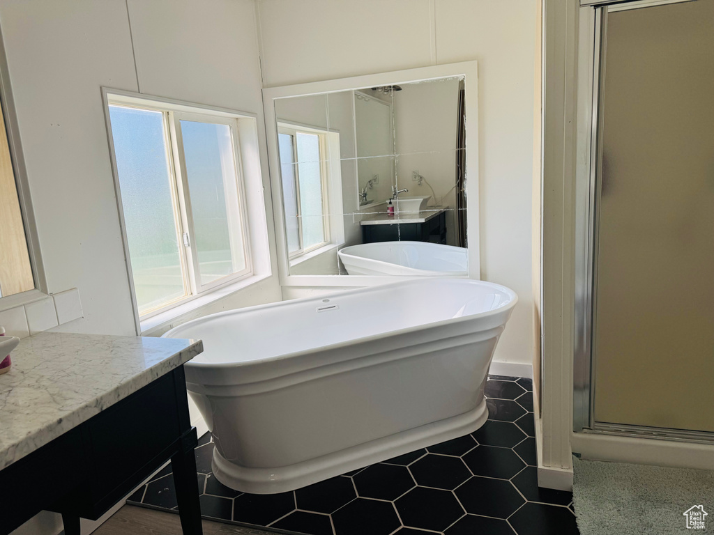 Full bathroom featuring vanity, a freestanding bath, a shower stall, and tile patterned floors
