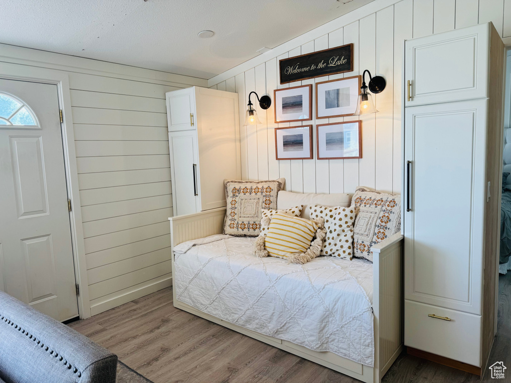 Bedroom featuring wood finished floors and wood walls
