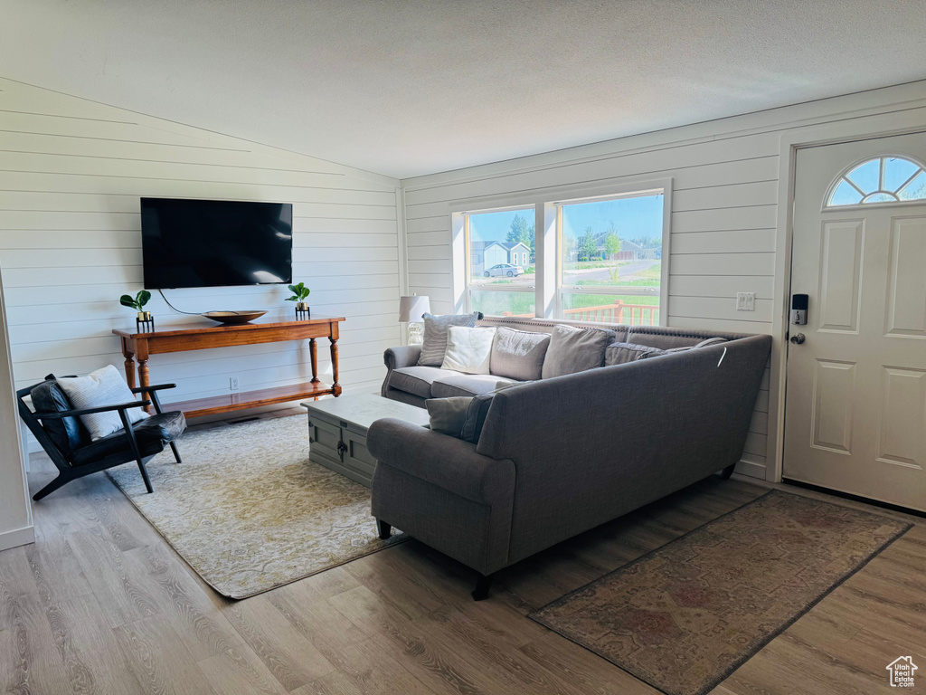 Living room featuring wood finished floors, lofted ceiling, and wooden walls