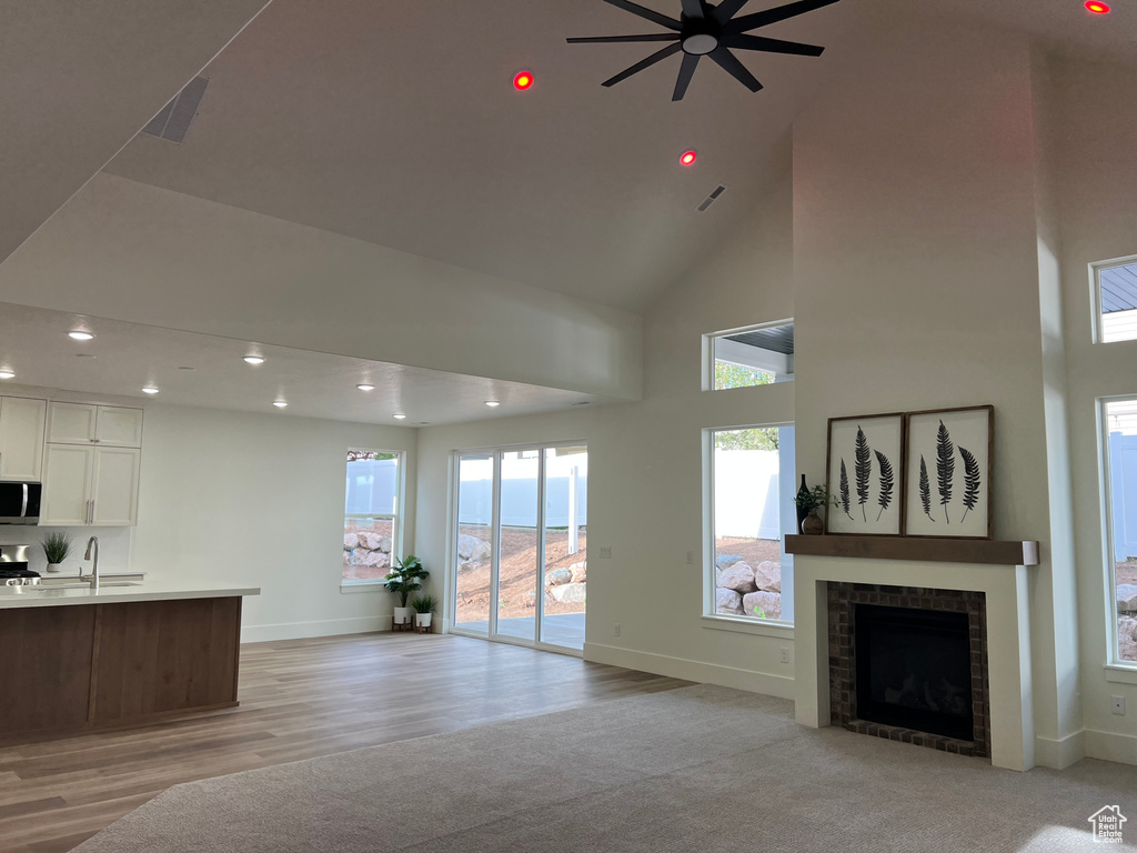 Living area featuring a ceiling fan, baseboards, light wood-style floors, a high ceiling, and recessed lighting