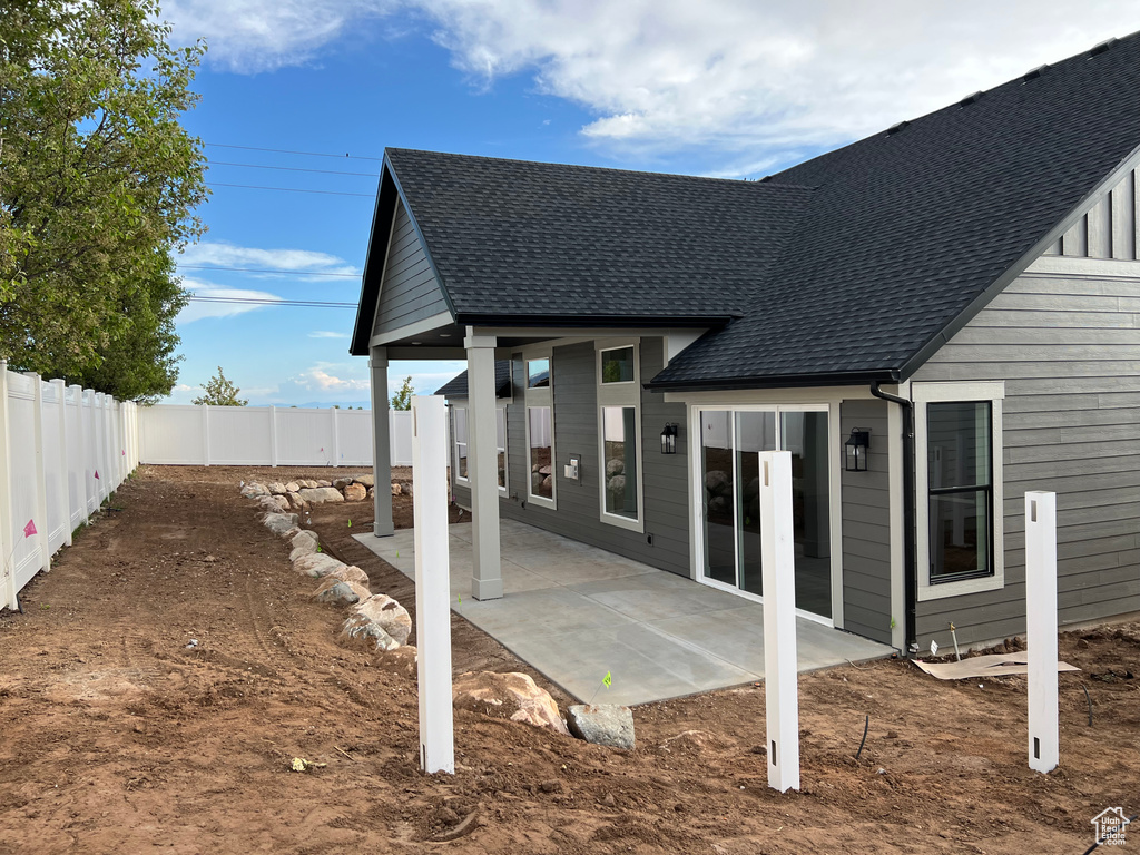 Back of property featuring a fenced backyard, a shingled roof, and a patio area