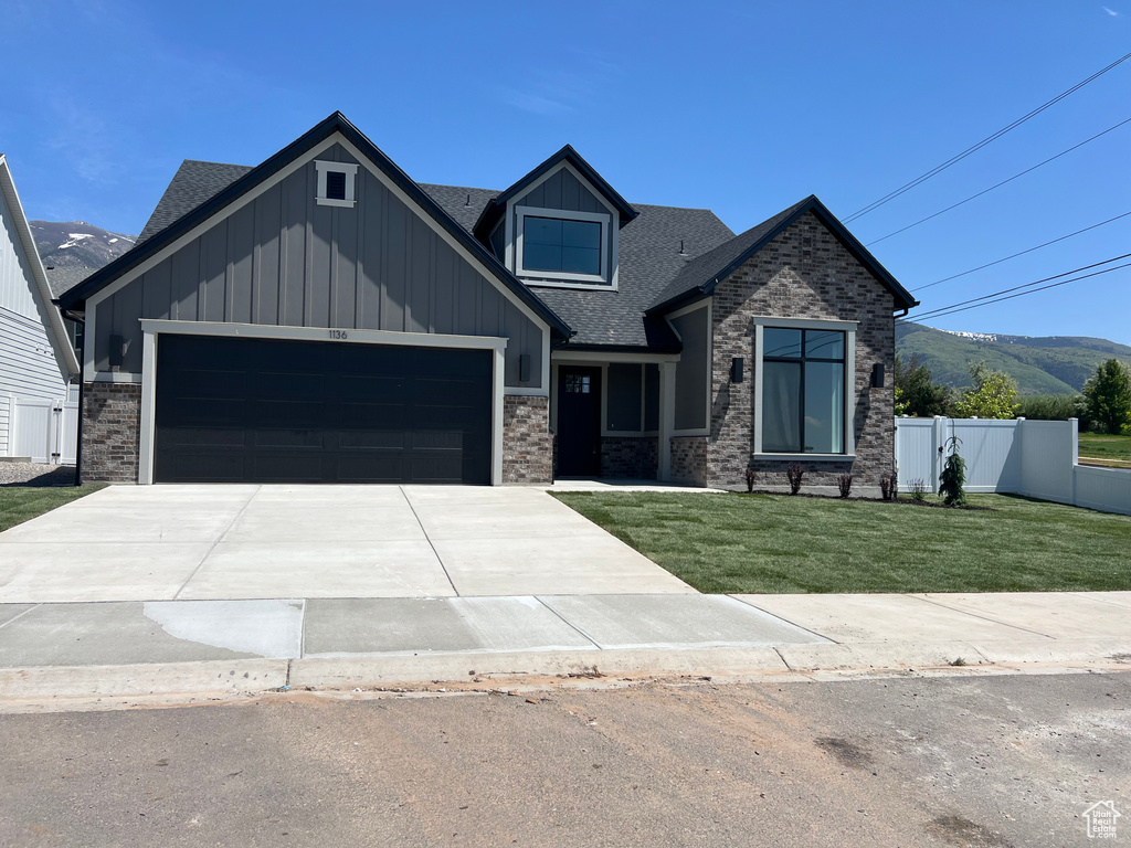 Craftsman-style home featuring an attached garage, roof with shingles, concrete driveway, board and batten siding, and a mountain view