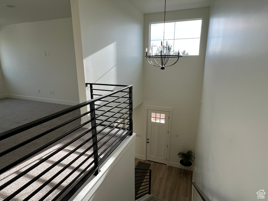 Stairs with baseboards, an inviting chandelier, wood finished floors, and a towering ceiling