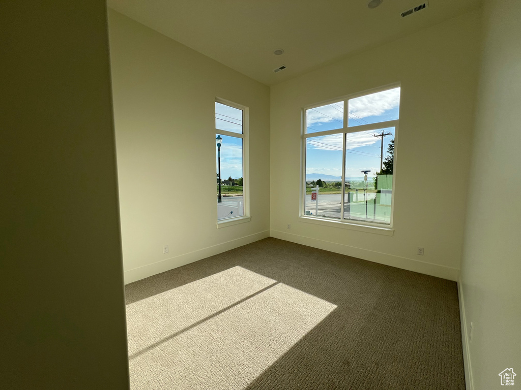 Unfurnished room with visible vents, baseboards, and dark carpet