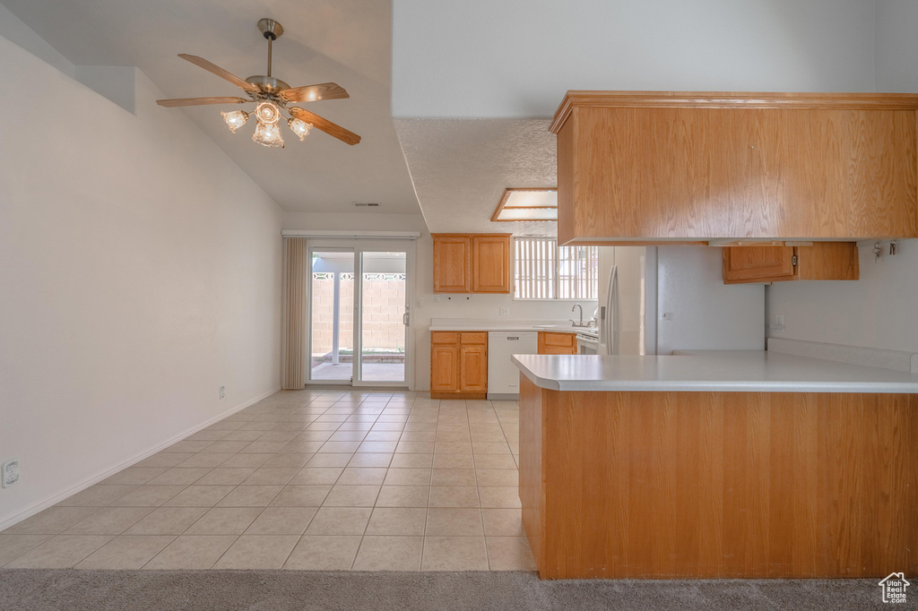 Kitchen featuring dishwasher, sink, kitchen peninsula, light tile patterned flooring, and ceiling fan