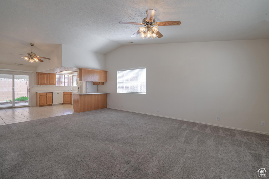 Unfurnished living room featuring a textured ceiling, light colored carpet, ceiling fan, and lofted ceiling