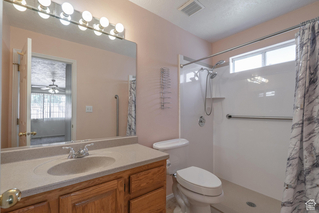 Bathroom featuring toilet, vanity, a textured ceiling, ceiling fan, and a shower with shower curtain