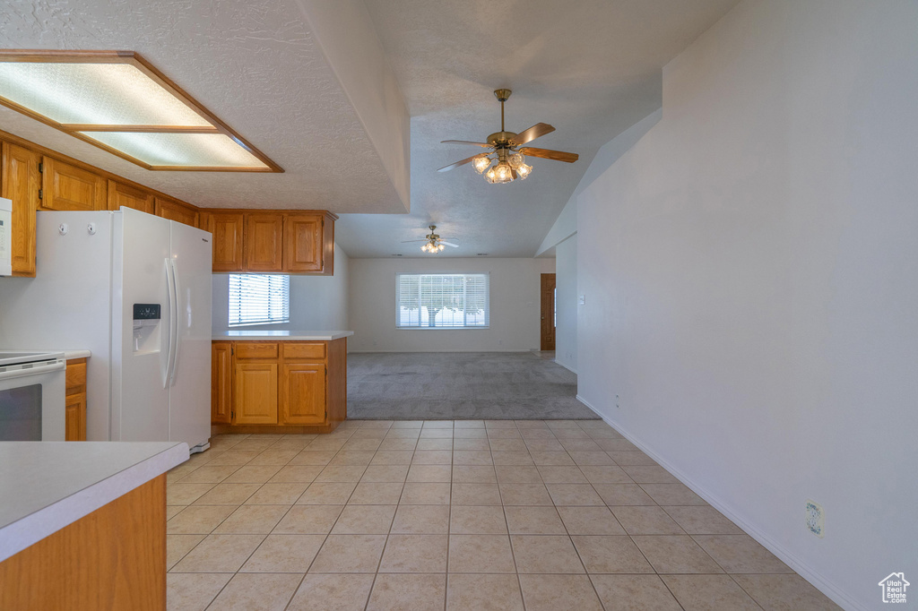 Kitchen with a textured ceiling, ceiling fan, light tile patterned floors, and white appliances