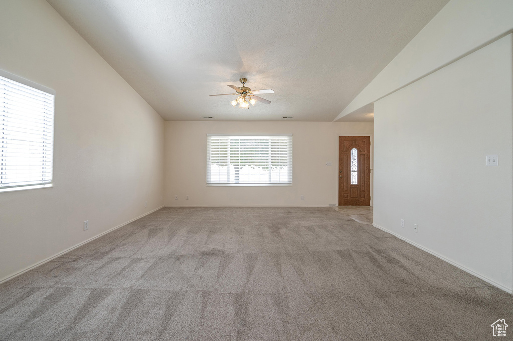 Carpeted spare room with vaulted ceiling, a textured ceiling, and ceiling fan