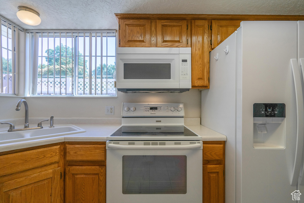 Kitchen featuring a textured ceiling, sink, and white appliances