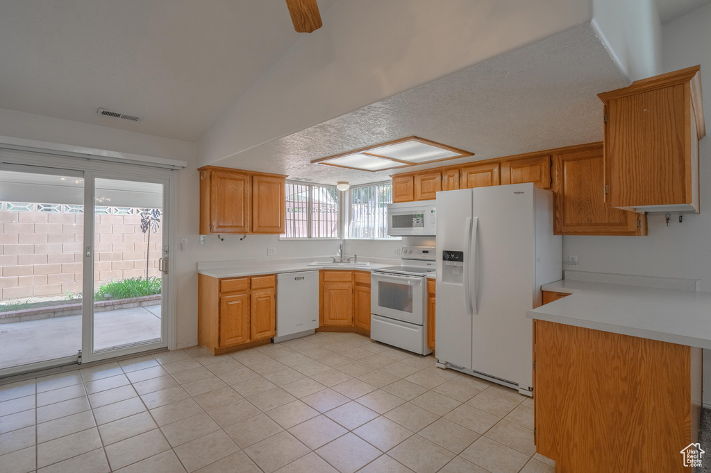 Kitchen featuring white appliances, light tile patterned floors, sink, ceiling fan, and vaulted ceiling