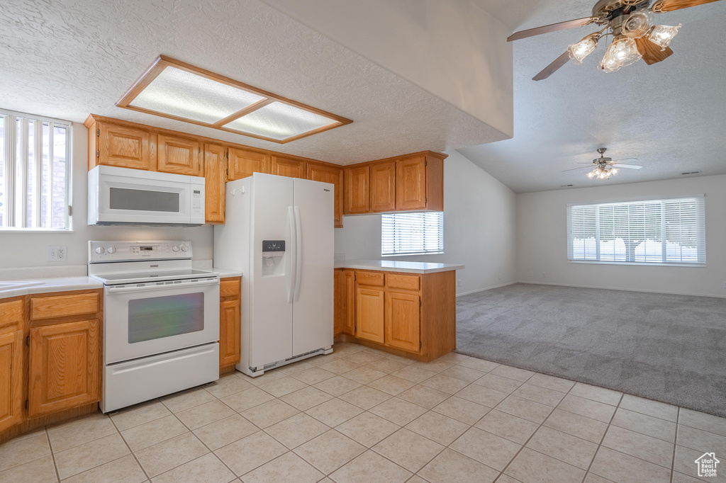 Kitchen with a textured ceiling, ceiling fan, light carpet, and white appliances