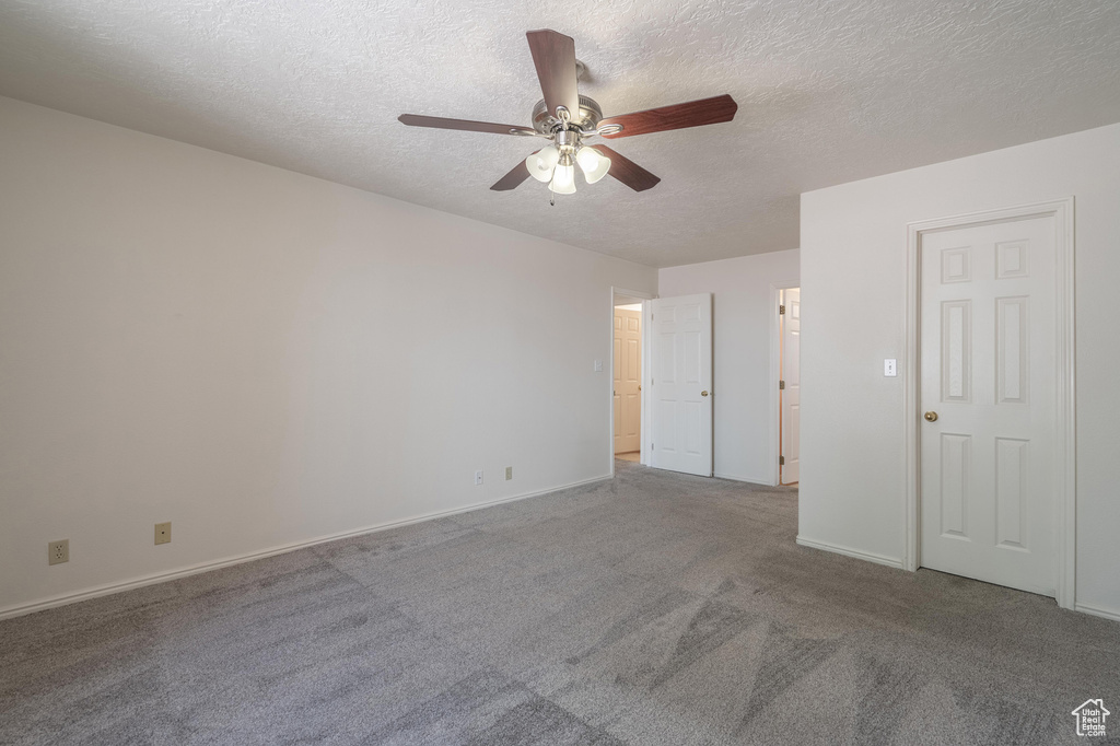 Carpeted empty room featuring a textured ceiling and ceiling fan