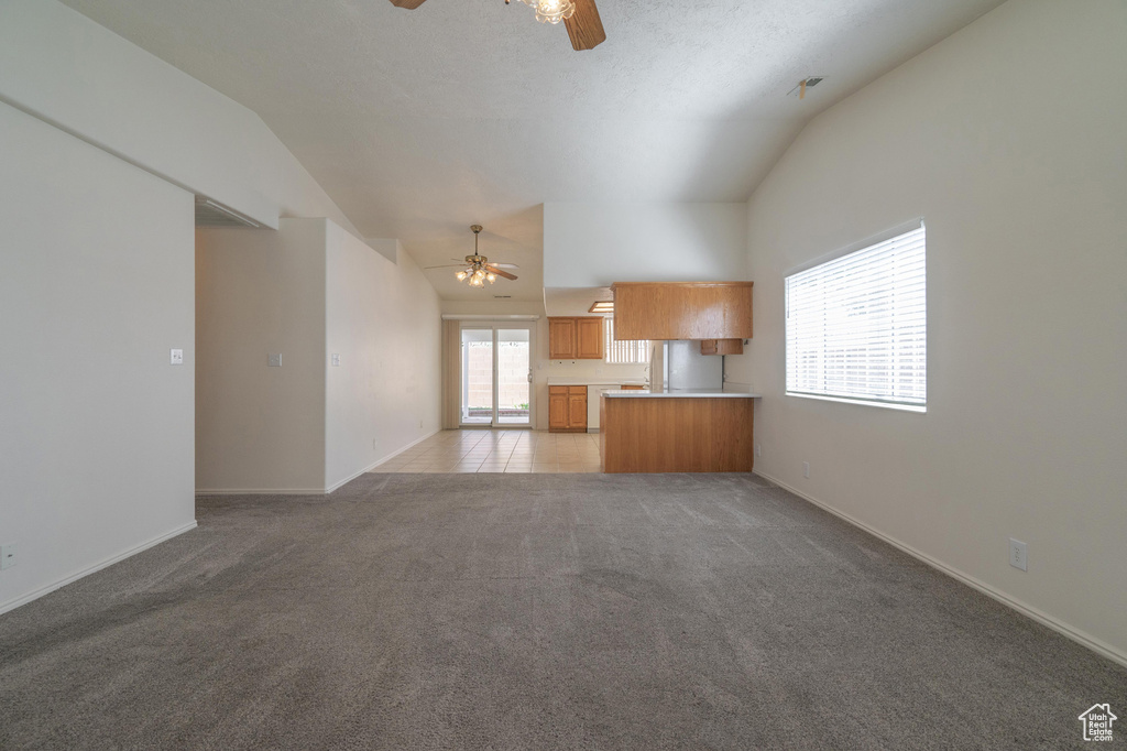 Unfurnished living room with lofted ceiling, light colored carpet, and ceiling fan