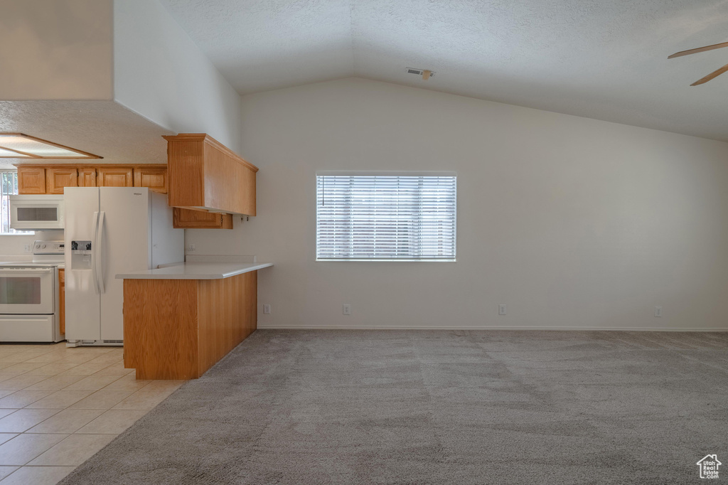 Kitchen with a textured ceiling, white appliances, light tile patterned floors, lofted ceiling, and ceiling fan