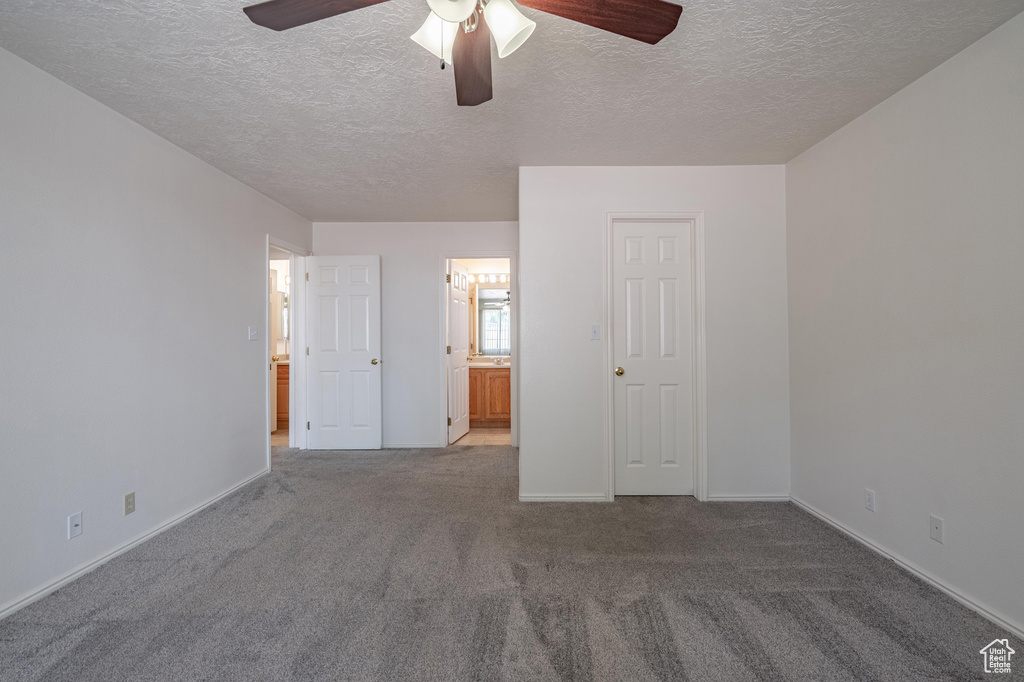 Unfurnished bedroom with a textured ceiling, ceiling fan, carpet floors, and ensuite bathroom