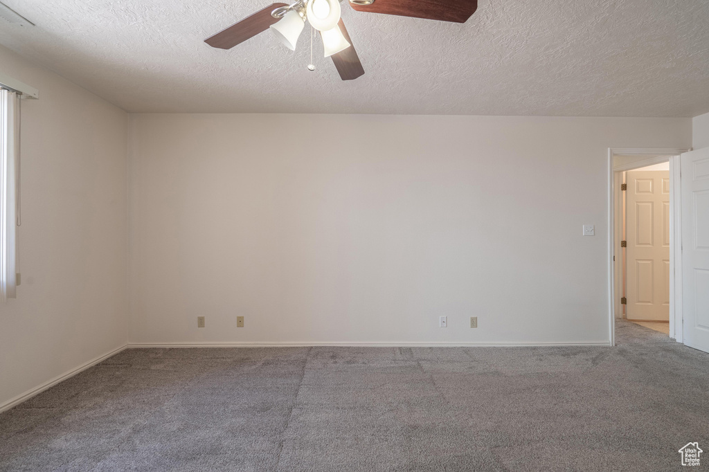 Carpeted spare room featuring a textured ceiling and ceiling fan