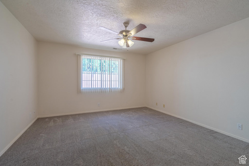 Unfurnished room with a textured ceiling, carpet, and ceiling fan