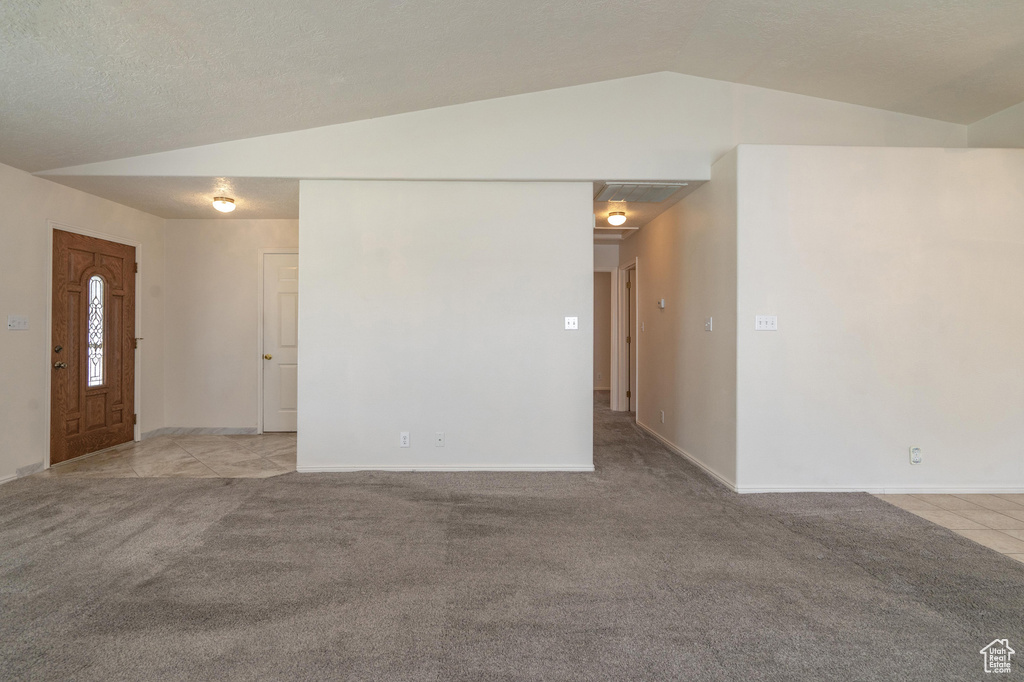 Carpeted empty room with lofted ceiling