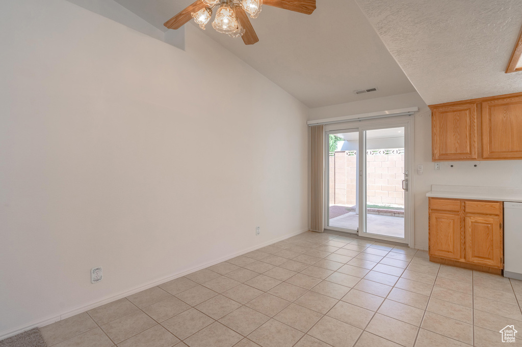 Unfurnished dining area with vaulted ceiling, a textured ceiling, light tile patterned floors, and ceiling fan