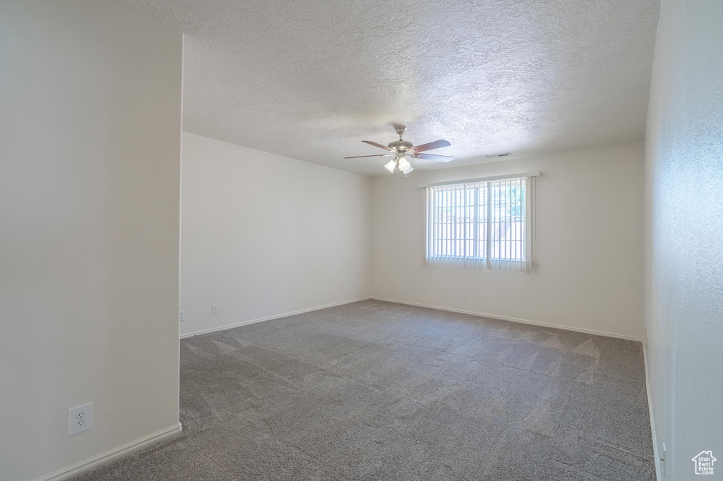 Spare room featuring a textured ceiling, ceiling fan, and carpet floors