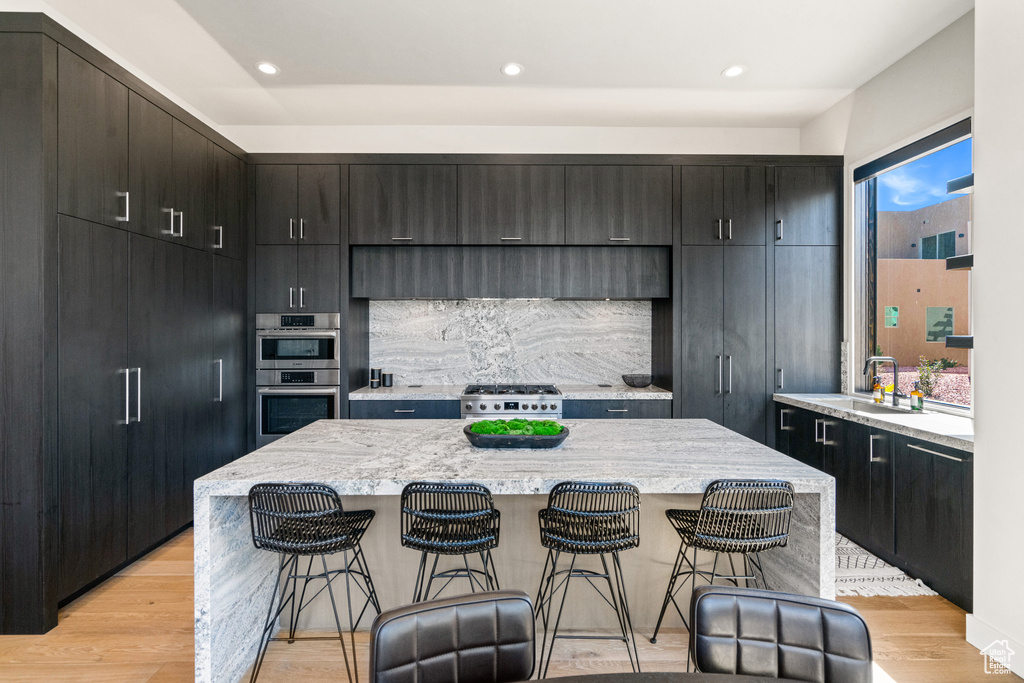 Kitchen with a kitchen island, sink, appliances with stainless steel finishes, and light hardwood / wood-style floors