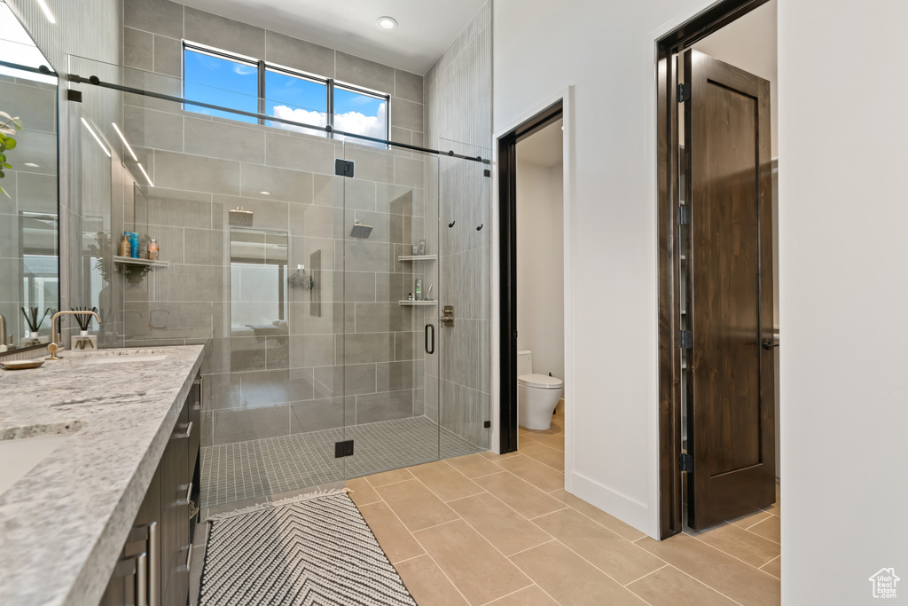 Bathroom featuring vanity, toilet, tile patterned floors, and a shower with door