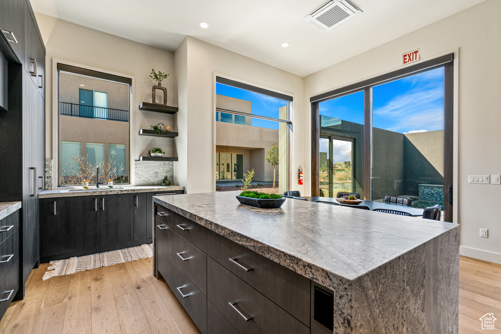 Kitchen with light wood-type flooring, a center island, and sink