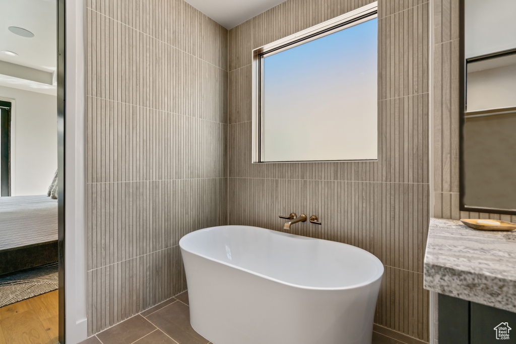 Bathroom with tile walls, vanity, a washtub, and tile patterned floors