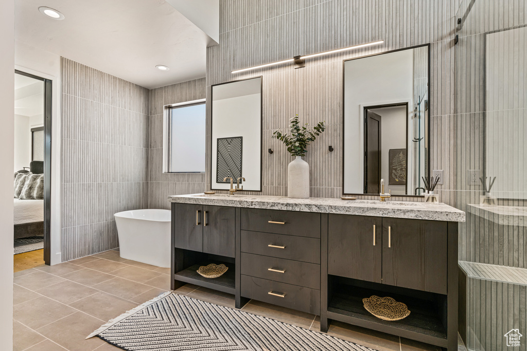 Bathroom with tile patterned floors, tile walls, a tub to relax in, and vanity